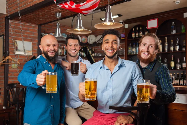 Grupo de hombres en el bar Clink Glasses Toasting, Beber tazas de sujeción de cerveza, Mix Race Cheerful Friends Wear Shirts —  Fotos de Stock