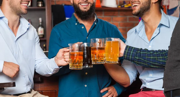 Grupo de hombres en el bar Clink Glasses tostadas sentarse en la mesa, beber cerveza celebrar tazas de cerca —  Fotos de Stock