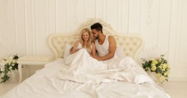 Tablet bilgisayar, mix yarış adam kadın gülümseme sabah yatak kullanarak yatakta yatan Çift