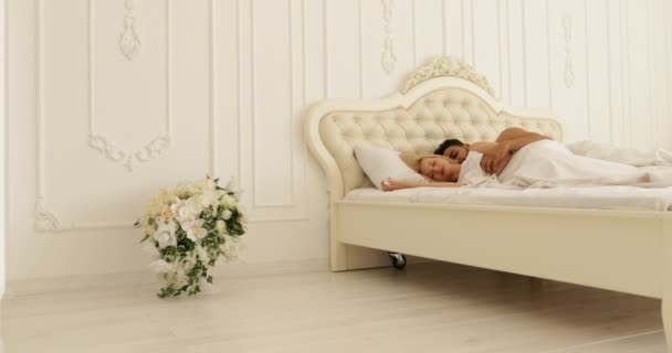 Couple dormir couché sur le lit homme étreinte femme maison blanc chambre moderne — Video