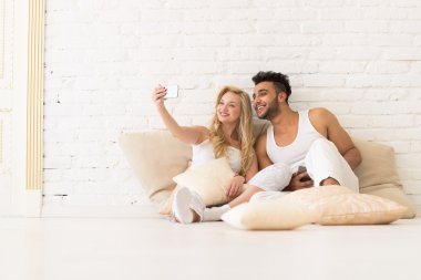 Young Couple Sit On Pillows, Girl Take Selfie Photo, Happy Smile Hispanic Man And Woman Hug Lovers