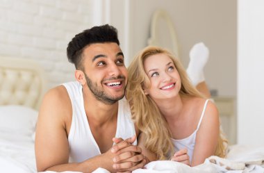 Genç çift yatak, mutlu gülümseme Hispanik erkek ve kadın sevenler yatak odasında yalan