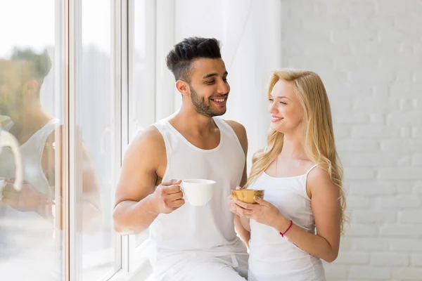 Young Beautiful Couple Stand Near Big Window, Drink Morning Coffee Cup, Happy Smile Hispanic Man And Woman — ストック写真