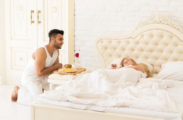 Hombre hispano llevar el desayuno a la mujer dormida en bandeja de la mañana con flor de rosa roja —  Fotos de Stock