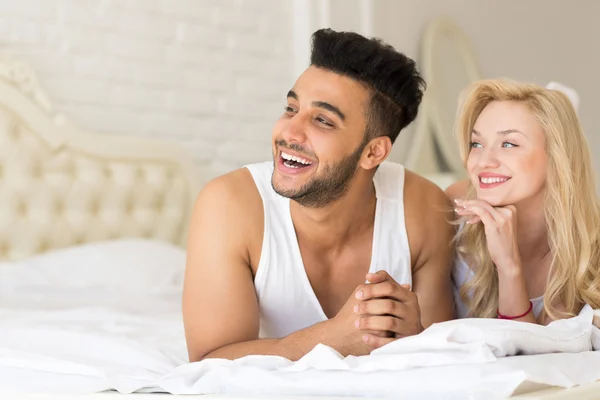 Pareja joven acostada en la cama, feliz sonrisa Hombre y mujer hispanos amantes en el dormitorio —  Fotos de Stock