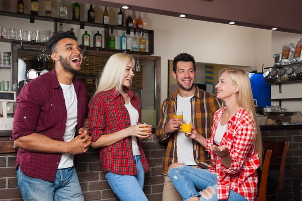 Lidé přátelé konzumní pomerančová šťáva rozhovor se smíchem sedět u baru, míchat závod muž a ženská dvojice — Stock fotografie
