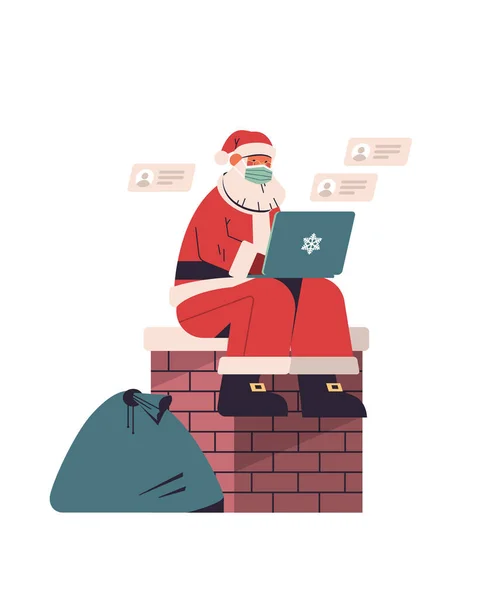 Santa Claus en máscara protectora sentado en la chimenea y el uso de la computadora portátil feliz año nuevo feliz celebración de las fiestas de Navidad — Vector de stock