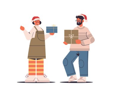Noel Baba şapkalı çift hediye paketlerini tutarken mutlu yıllar ve mutlu noeller.