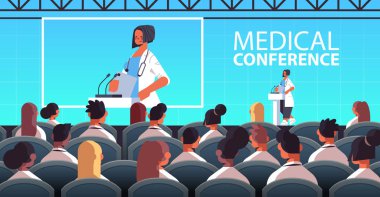 Tribünde mikrofon konferansı tıbbi sağlık hizmetleriyle konuşma yapan kadın doktor.