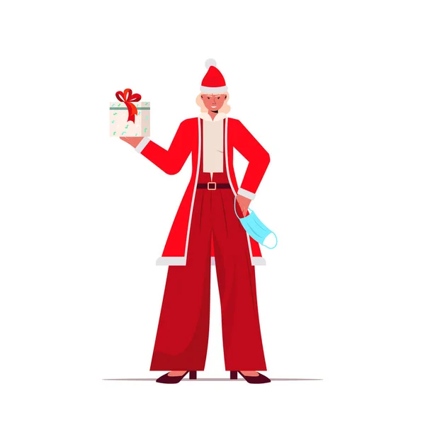 Santa žena s maskou držení dárkové krabice Nový rok vánoční svátky oslavy coronavirus karanténa koncept — Stockový vektor