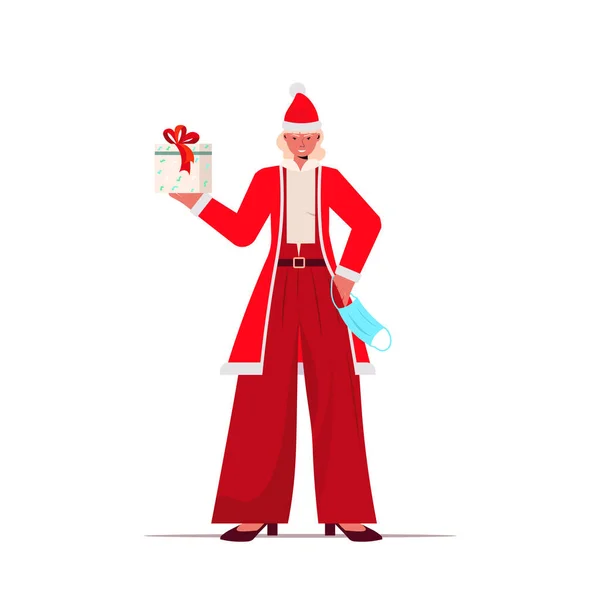 Santa mujer con máscara celebración caja de regalo año nuevo Navidad fiesta celebración coronavirus cuarentena concepto — Vector de stock