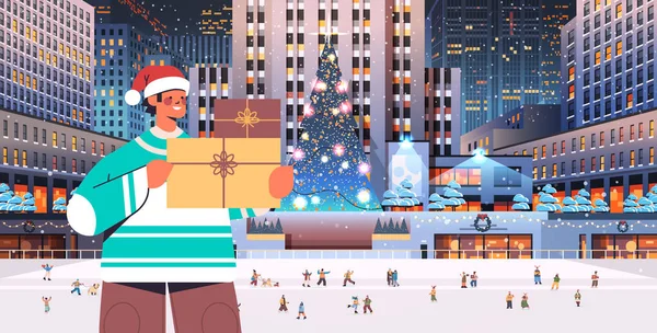 Muž v Santa klobouk držení dárkové krabice veselé Vánoce šťastný nový rok zimní svátky koncepce oslav — Stockový vektor