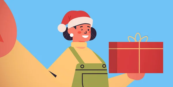 Glückliche Frau im Weihnachtsmannhut mit Geschenkbox, Kamera in der Hand und Selfie von der Weihnachtsfeier im neuen Jahr — Stockvektor