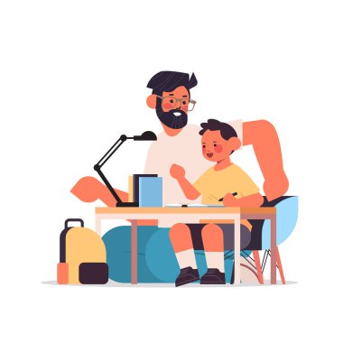 Baba oğluna ev ödevi yaparken yardım ediyor. Babalık, aile kavramı. Baba çocuğuyla vakit geçiriyor.