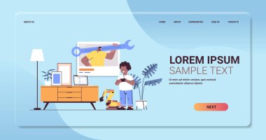 Afro-Amerikan okul çocuğu radyo kontrollü traktörle oynuyor ve tamirat uzmanıyla konuşuyor.