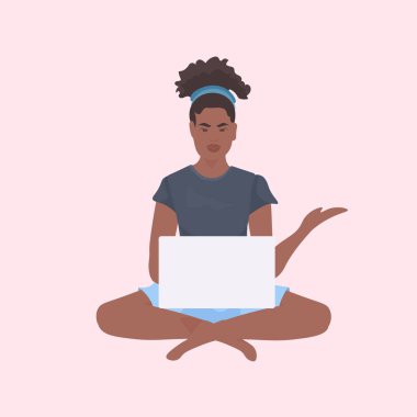 Lotus pozisyonunda oturan genç bir kadın dizüstü bilgisayar serbest konsepti üzerinde çalışıyor.