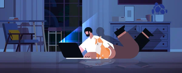 暗い夜の家の部屋に床に横たわっている犬とノートパソコンの画面の男を見て過労のビジネスマンのフリーランサー — ストックベクタ