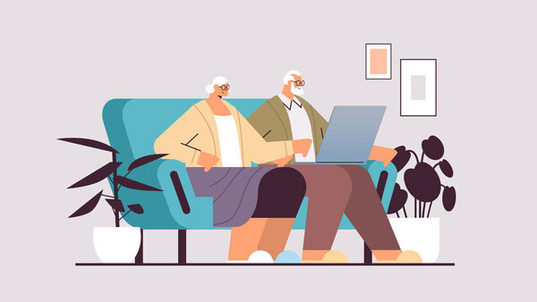 senior couple using laptop grandparents relaxing on sofa at home social media network online communication concept
