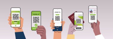 Dijital aşı sertifikalı ve küresel dokunulmazlık pasaportlu akıllı telefonları tutan eller