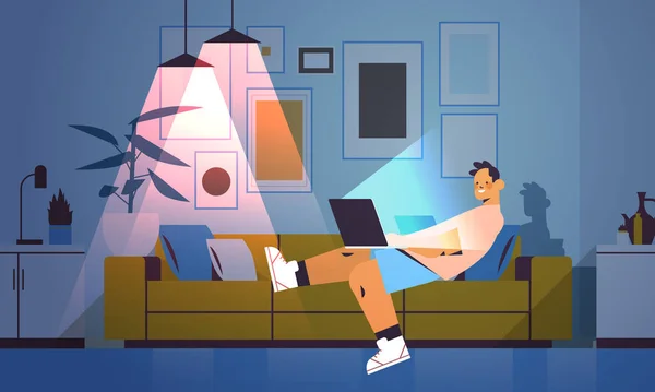 Школьник смотрит на экран ноутбука подросток лежит на диване в темной ночи домашней комнате — стоковый вектор