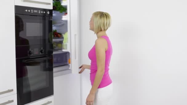 Женщина получает яблоко из холодильника — стоковое видео