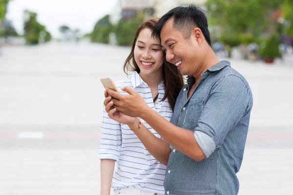 Asijský pár buněk chytrý telefon zprávy úsměv — Stock fotografie