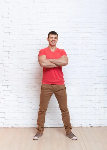 Mladý muž s úsměvem složené ruce stojí přes zeď — Stock fotografie