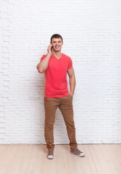 Příležitostné muž mobilního telefonu a hovor hovoří Smartphone stojan přes zeď — Stock fotografie