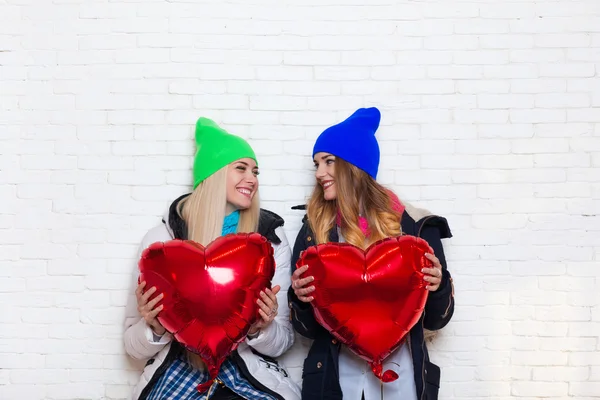 Due ragazze amiche si guardano a vicenda con palloncini a forma di cuore rosso San Valentino — Foto Stock