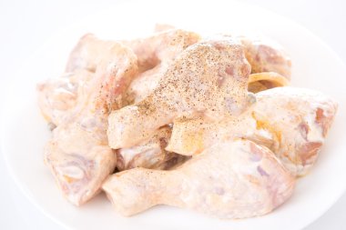 Beyaz arka planda çiğ tavuk budu.