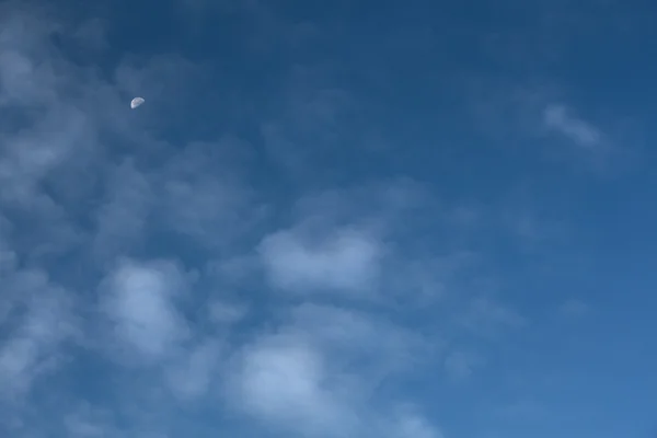 Céu azul com meia lua e nuvens Wispy — Fotografia de Stock