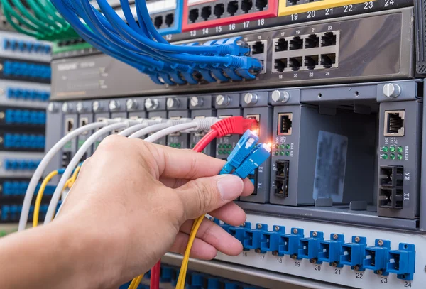 Hombre que trabaja en la sala de servidores de red con concentrador de fibra óptica para digi —  Fotos de Stock