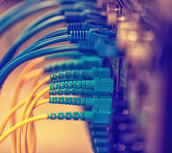 Glasfaserkabel, die mit einem optischen Port und einem Netzwerkkabel verbunden sind — Stockfoto