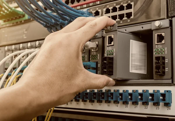 Man som arbetar i nätverk serverrum med fiber optic nav för digi — Stockfoto