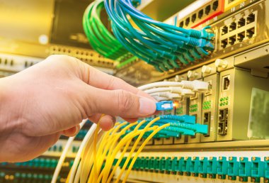 Dijital iletişim ve internet için fiber optik merkezi olan ağ sunucu odasında çalışan adam