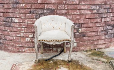 Terk edilmiş eski evin önünde mavi kanepe var.