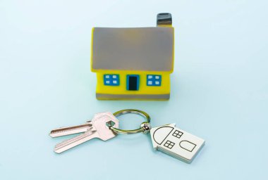 Ev sembollü anahtarlık ve mavi arka planda anahtarlık, gayrimenkul kavramı