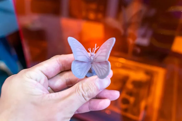 3Dプリンタで印刷された蝶のおもちゃの形のオブジェクトと手 — ストック写真