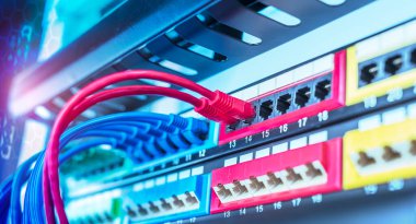Veri sunucu odasındaki yama paneline bağlı mavi ve kırmızı internet yama kablosu olan sunucu rafı