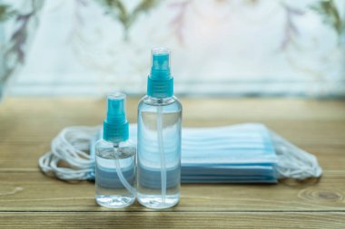 Coronavirus koruması. El dezenfektanı şişesi ve masadaki tıbbi koruyucu cerrahi maskeler..
