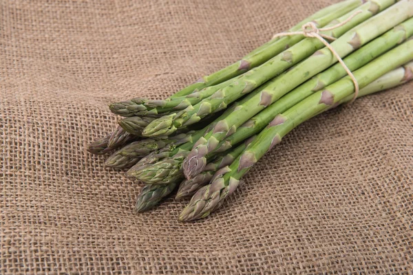 Färsk grön sparris groddar handpåläggning bambu bakgrund — Stockfoto