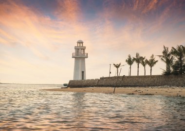 Güneşin doğuşunda deniz feneri olan güzel deniz manzarası
