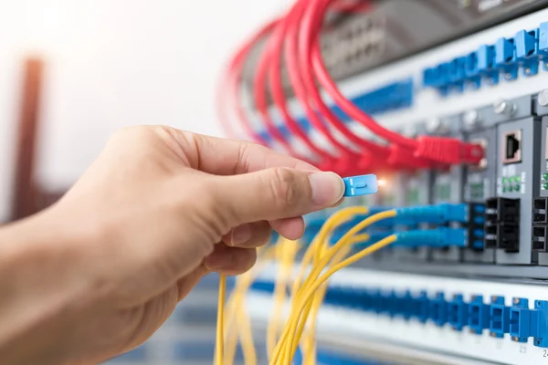 Uomo che collega cavi di rete in fibra ottica agli interruttori — Foto Stock