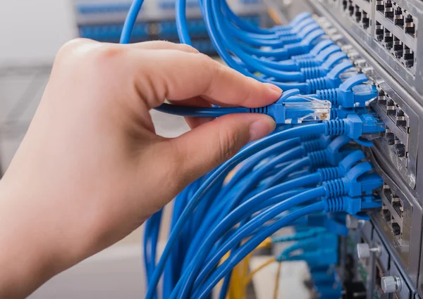 Man connecting network cable to switch — Stock Photo, Image