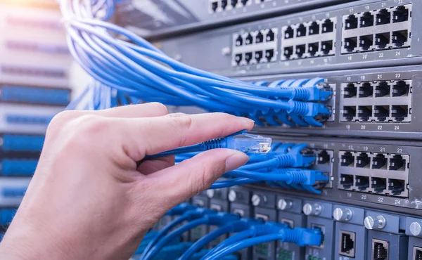 Man connecting network cable to switch — Stock Photo, Image