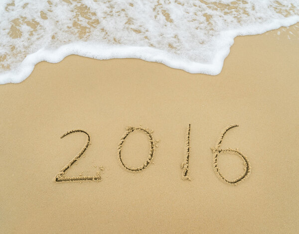Рука 2016 года написана на белом песке перед морем
