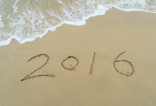 Año 2016 mano escrita en la arena blanca frente al mar —  Fotos de Stock