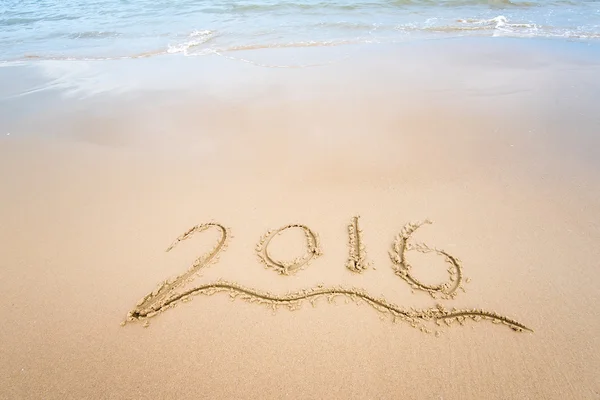 Año 2016 mano escrita en la arena blanca frente al mar —  Fotos de Stock