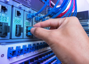 man working in network server room with fiber optic hub for digi clipart