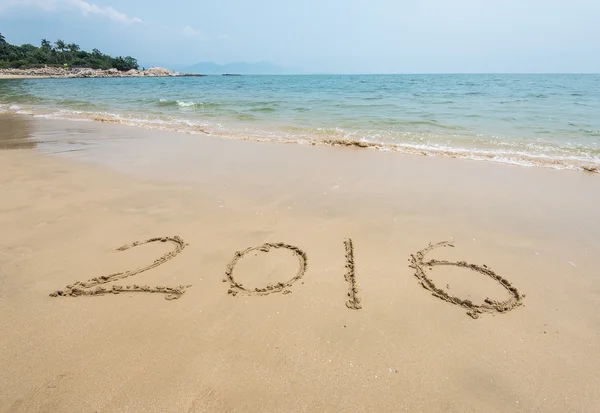 Año 2016 mano escrita en la arena blanca frente al mar —  Fotos de Stock